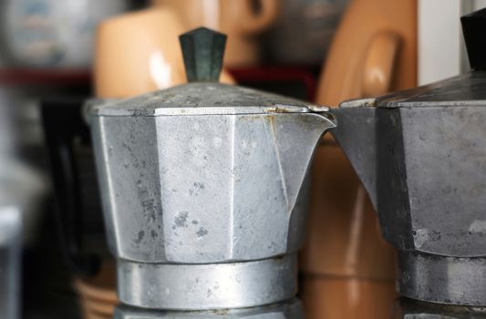 Close-up view of an old rusty coffee pot inside a pantry. Scratches and signs of wear near the spout. Design object. Italian culture