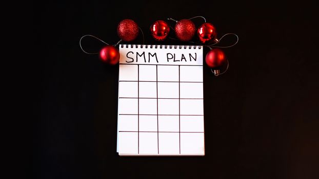 Freelance project. SMM plan blank. White sheet on a black festive background with red Christmas balls