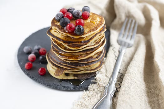 Plate with pancakes and berries on white table.