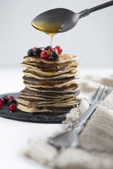 Plate with pancakes and berries on white table.