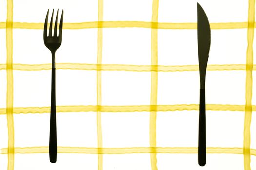 spaghetti pasta laid out in the form of a cell background texture with fork and knife