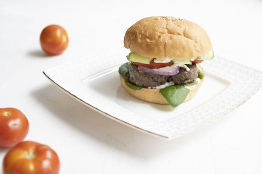 Milanese burger, with tomatoes, lettuce and french fries, in white background.