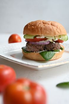 Milanese burger, with tomatoes, lettuce and french fries, in white background.