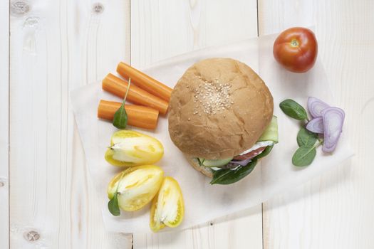 Milanese burger, with tomatoes, lettuce and french fries, in white background.