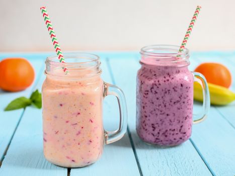 Blueberry smoothie with mint in mason jar with straw against a wood background.