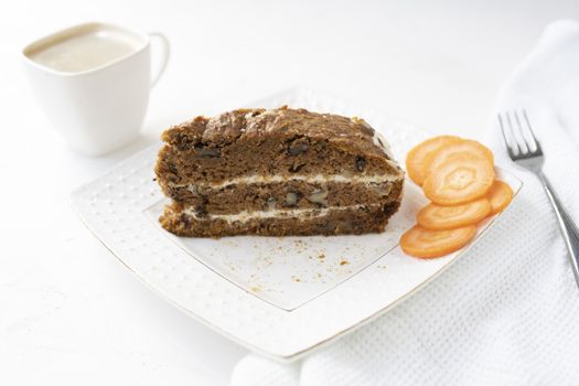Slice of carrot cake and coffee on white background.