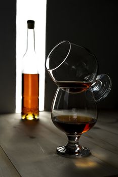 Bottle and glass of cognac over dark and white background.