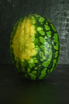A whole big watermelon on a black table background.