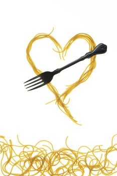 Swirls of cooked spaghetti with fork. Spaghetti heart shape