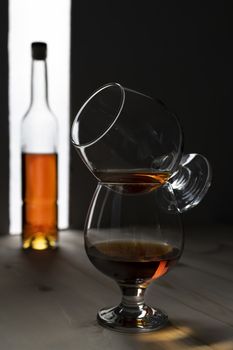 Bottle and glass of cognac over dark and white background.