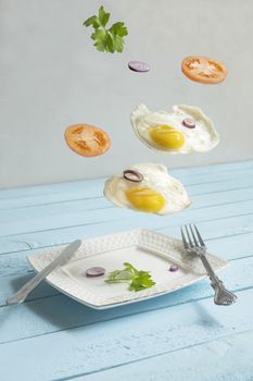 two flying levitated fried eggs, tomats and punch.