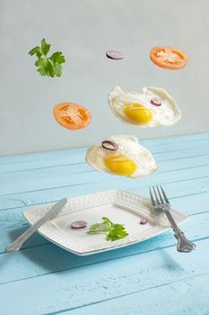 two flying levitated fried eggs, tomats and punch.