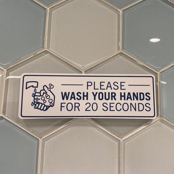 A sign in a public restroom that tells people to please wash your hands for 20 seconds due to the coronavirus pandemic.