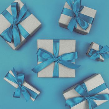 Gift boxes wrapped in craft paper with a blue ribbons and bows. Festive monochrome flat lay.