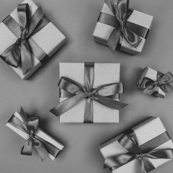 Gift boxes wrapped in craft paper with a black ribbons and bows. Festive monochrome flat lay.