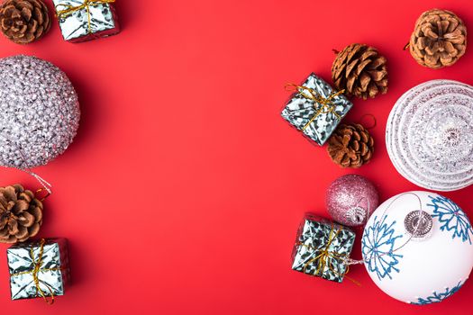 Christmas New Year composition. Gifts, fir tree cones, silver ball decorations on red background. Winter holidays concept. Flat lay, top view, copy space