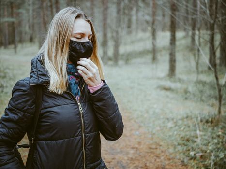 Beautiful european Women Wearing Protective Mask Outside Pretty young girl in medical black face mask in a forest. covid19 concept. modern reality. copy space. 2020, allergy. Autumn season. Copy space