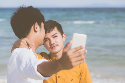 Gay portrait young couple smiling taking a selfie photo together with smart mobile phone at beach, LGBT homosexual lover in the vacation at sea, two man going to travel, holiday concept.