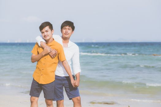 Homosexual portrait young asian couple standing hug together on beach in summer, asia gay going tourism for leisure and relax with romantic and happiness in vacation at sea, LGBT concept.