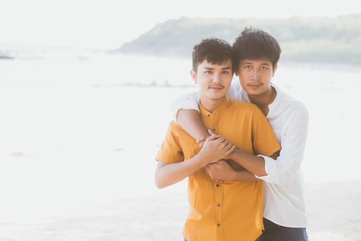 Homosexual portrait young asian couple standing hug together on beach in summer, asia gay going tourism for leisure and relax with romantic and happiness in vacation at sea, LGBT concept.