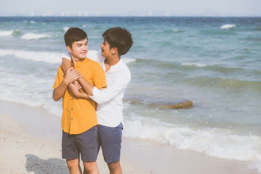 Homosexual portrait young asian couple standing hug together on beach in summer, asia gay going tourism for leisure and relax with romantic and happiness in vacation at sea, LGBT concept.