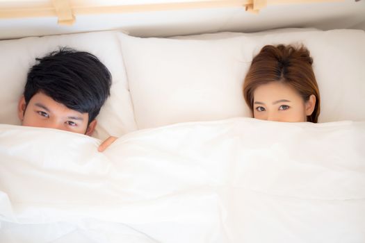 Beautiful young asian couple smiling lovely hiding blanket at bed together, man and woman fun and happy lying covering blanket, family feeling romantic and love, lifestyle concept, top view.