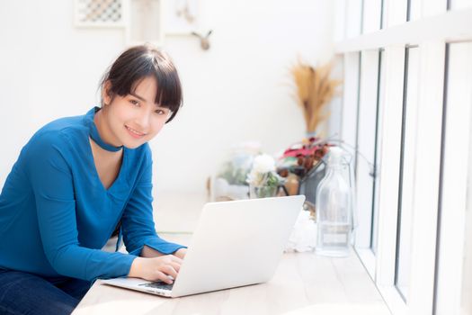 Beautiful portrait asia young woman working online on laptop sitting at cafe shop, professional female freelance using notebook computer, business and communication concept.