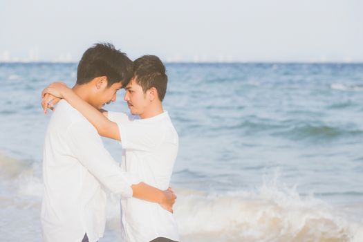 Homosexual portrait young asian couple standing hug together on beach in summer, asia gay going tourism for leisure and relax with romantic and happy in vacation at sea, LGBT legal concept.