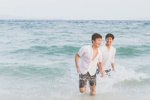 Homosexual portrait young asian couple running with cheerful together on beach in summer, asia gay going tourism for leisure and relax with happiness in vacation at sea, LGBT legal concept.