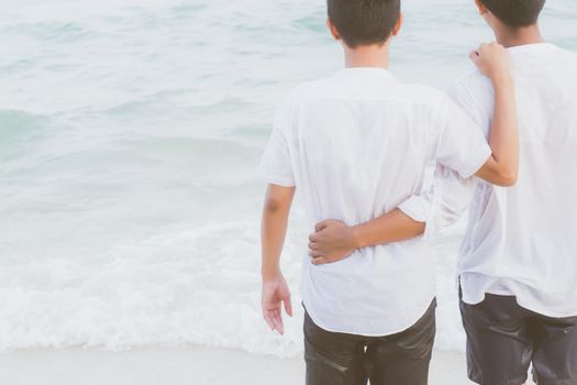 Back view homosexual portrait young asian couple standing hug and look together on beach in summer, asia gay going tourism for leisure and relax with happy in vacation at sea, LGBT legal concept.