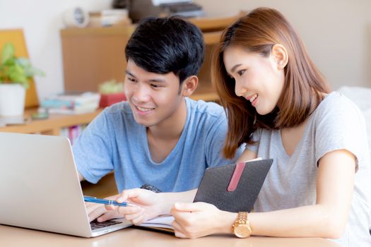 Beautiful young asian couple calculate expenses finance with laptop and planning together, woman writing notebook or note budget household, lifestyle family and business concept.