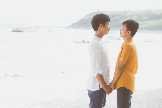 Homosexual portrait young asian couple standing together on beach in summer, asia gay holding hands going sea for leisure and relax with romantic and happy in vacation at sea, LGBT with legal concept.