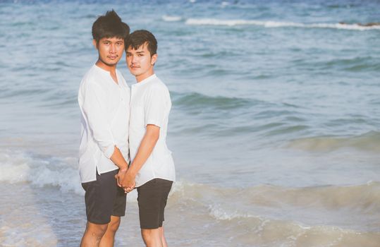 Homosexual portrait young asian couple standing together on beach in summer, asia gay holding hands going sea for leisure and relax with romantic and happy in vacation at sea, LGBT with legal concept.