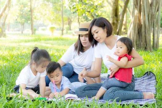 Beautiful young asian parent family portrait picnic in the park, kid or children and mother love happy and cheerful together in summer at garden, lifestyle concept.