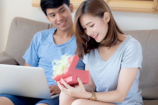 Young asian couple celebrate birthday together, asia man giving gift box present to woman for surprise at living room, female feeling happy and excited anniversary, holiday valentine concept.