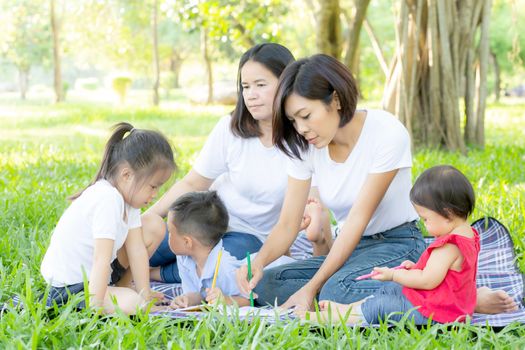 Beautiful young asian parent family portrait picnic in the park, kid or children and mother love happy and cheerful together in summer at garden, lifestyle concept.