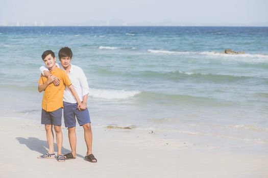 Homosexual portrait young asian couple standing hug together on beach in summer, asia gay going tourism for leisure and relax with romantic and happiness in vacation at sea, LGBT concept.