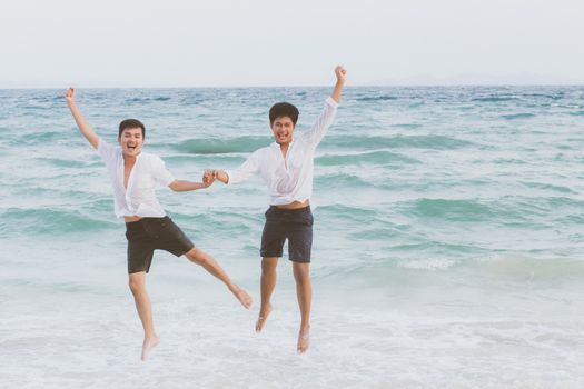 Homosexual portrait young asian couple running and jump with cheerful together on beach in summer, asia gay going tourism for leisure and relax with happiness in vacation at sea, LGBT legal concept.