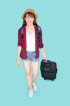 Beautiful young asian woman pulling suitcase isolated on blue background, asia girl having expression is cheerful holding luggage walking in vacation with excited, journey and travel concept.