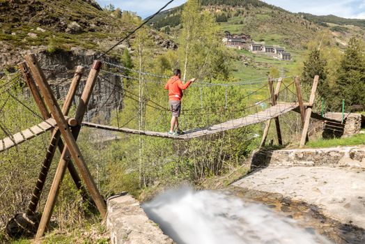 Canillo, Andorra : 6 mat 2020 :  Man in the Suspension bridge over the Rio de la Bor, Canillo in Anodrra in spring
