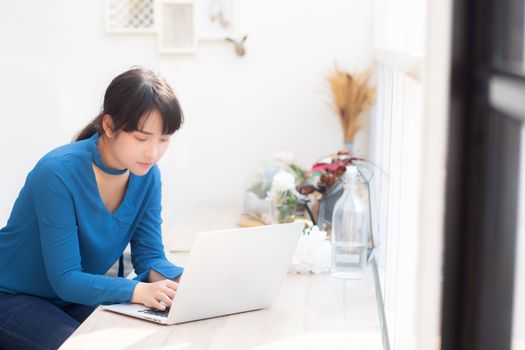 Beautiful portrait asia young woman working online on laptop sitting at cafe shop, professional female freelance using notebook computer, business and communication concept.