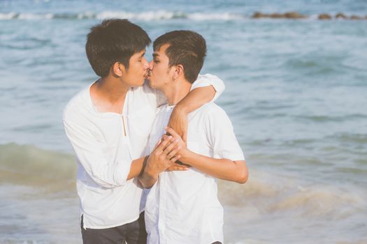 Homosexual portrait young asian couple standing hug and kiss mouth together on beach in summer, asia gay going tourism for leisure with romantic and happiness in vacation at sea, LGBT legal concept.