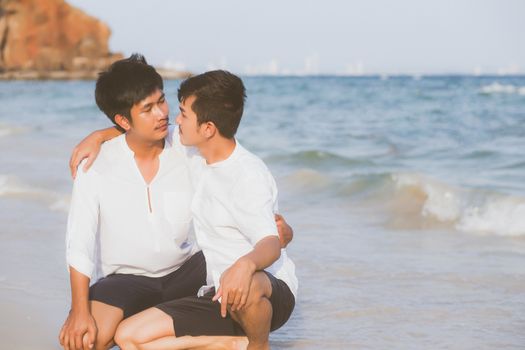 Homosexual portrait young asian couple sitting hug together on beach in summer, asia gay going tourism for leisure and relax with romantic and happiness in vacation at sea, LGBT legal concept.