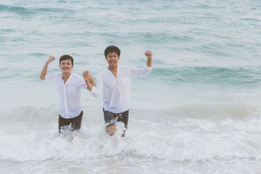 Homosexual portrait young asian couple running with cheerful together on beach in summer, asia gay going tourism for leisure and relax with happiness in vacation at sea, LGBT legal concept.