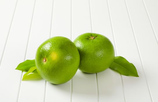 Two whole sweetie fruits (green grapefruits, pomelits) and leaves