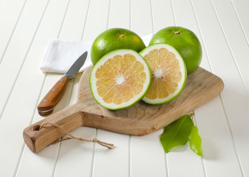 Sweetie fruits (green grapefruits, pomelits) - two whole fruits and slices - on cutting board