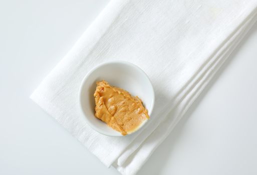 Bowl of crunchy peanut butter on white napkin