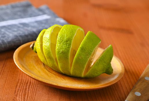 Lemon with green peel and yellow flesh, sliced on wooden plate