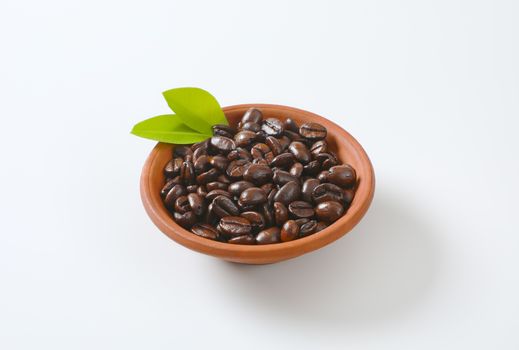 Roasted coffee beans in terracotta bowl