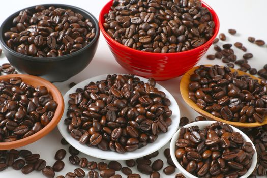 Roasted coffee beans in various bowls and on plate